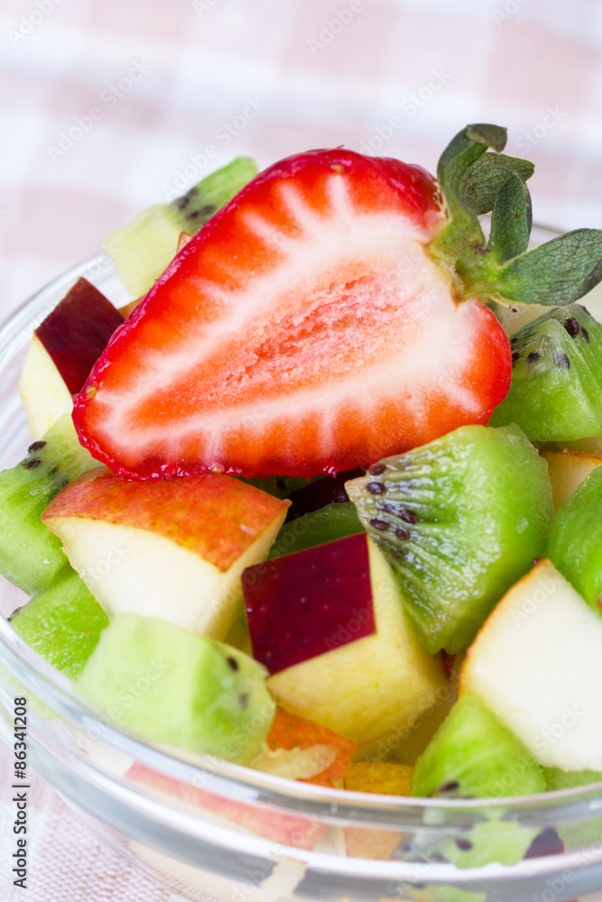 Fruit salad in white plate on tablecloth