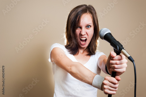 Young adult girl singing with microphone. color image