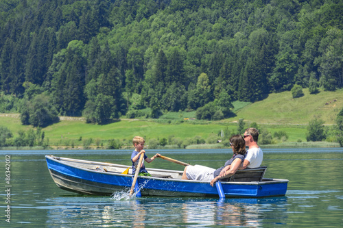 kleiner Junge fährt Ruderboot mit den Eltern