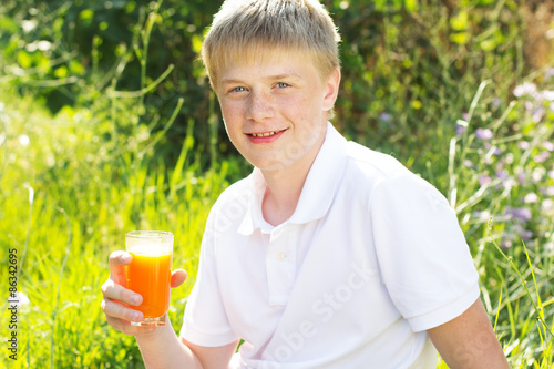 Young boy is holding glass with carrot juice