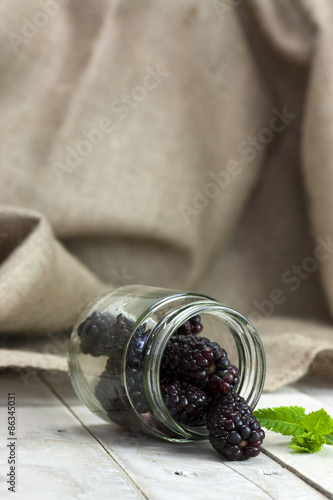 Blackberries in a jar and spilt on table