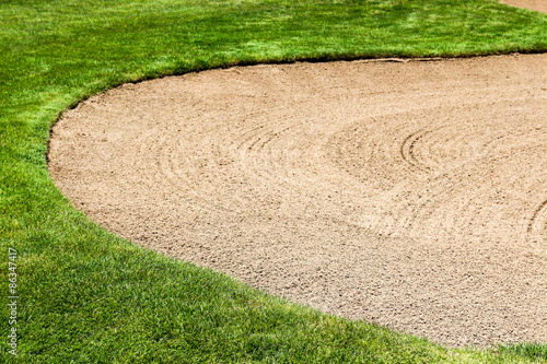 Curving raked sand in a sand trap at a golf course with copy space