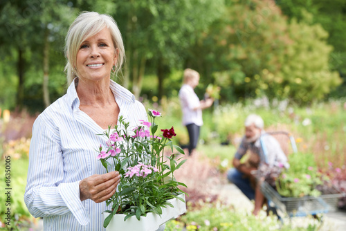 Mature Woman Choosing Plants At Garden Center