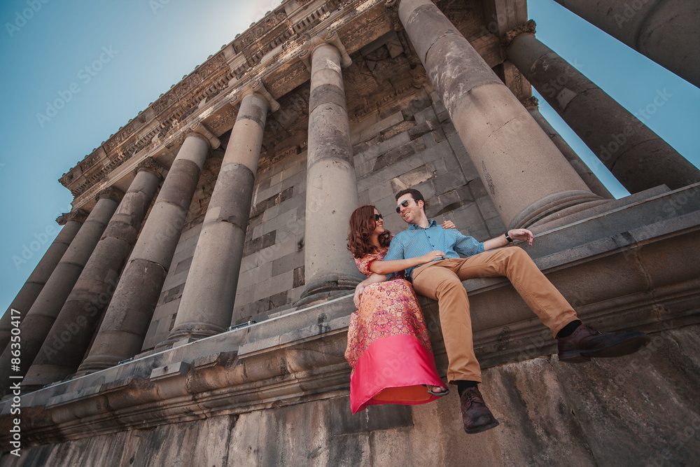 Fototapeta premium Young couple sitting near the ancient temple of Garni in Armenia