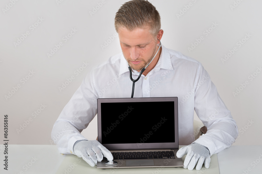 Technician Examining Laptop With Stethoscope Technician Examining Laptop With Stethoscope
