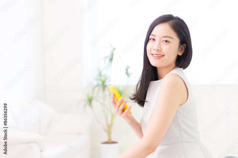 部屋でスマホを見る女性