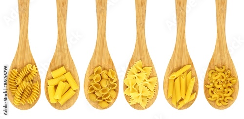 Wooden cooking spoons filled with various types dry pasta
