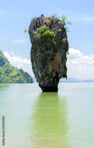 Rock hill and tree on green sea water