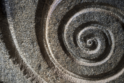Close-up of spiral pattern carved in rough stone in an ancient Hindu shrine in India