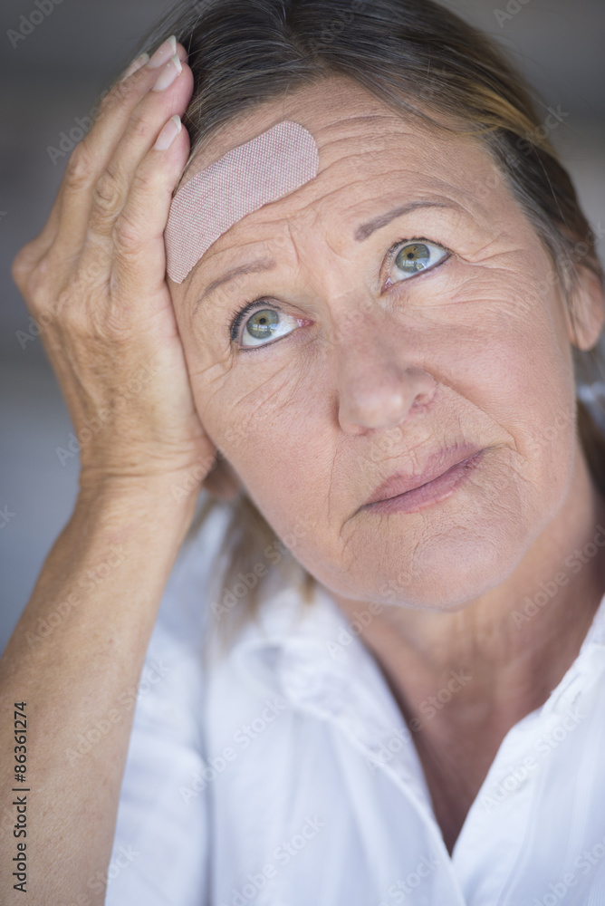 Woman in pain and band aid on forehead Woman in pain and band aid on forehead