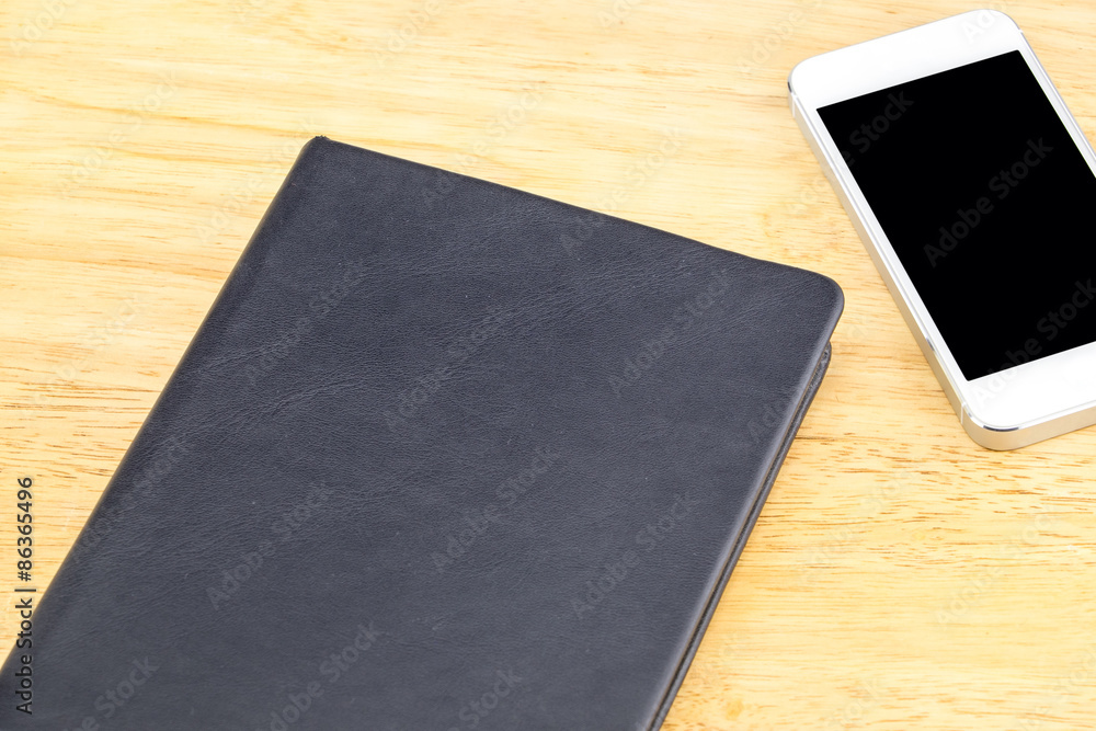 Close black blank notebook and mobile on wooden table,Mock up fo Close black blank notebook and mobile on wooden table,Mock up fo