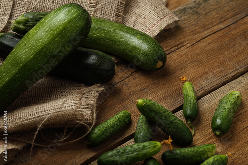 Zucchini and cucumbers on wooden background.
