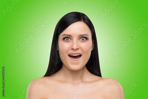 Portrait of an astonished brunette girl. Green background. photo