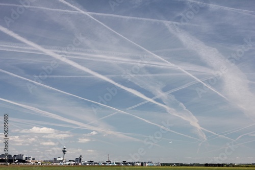 Schilderij op canvas Kondensstreifen am Himmel über dem Flughafen Amsterdam-Schiphol