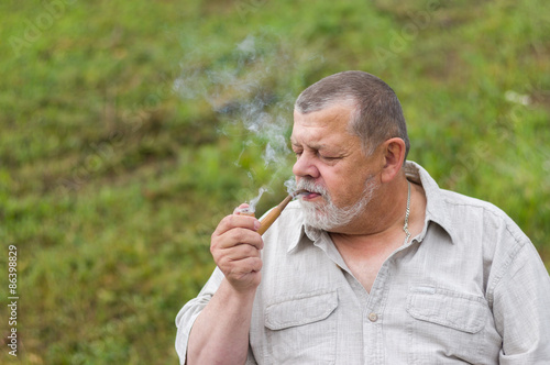 Outdoor portrait of a senior man smoking tobacco-pipe