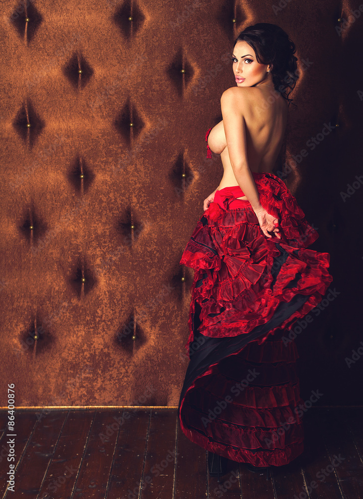 Sexy beautiful brunette woman dancing striptease in red skirt with naked breasts on a luxury velvet background - obrazy, fototapety, plakaty 
