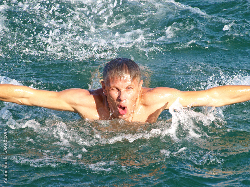 Man swims in the sea waves.