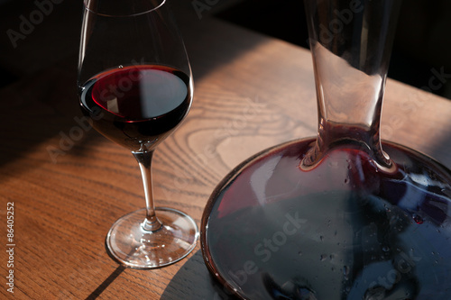 Closeup of the carafe and glass of red wine on the wooden table photo