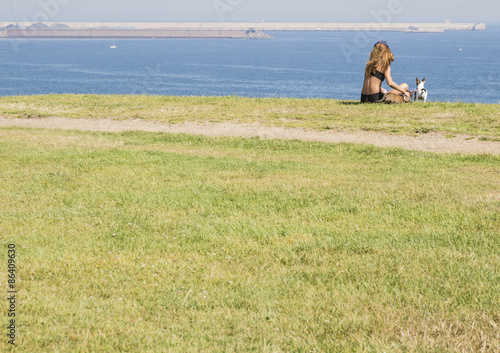 Chica sentada con perros frente al mar