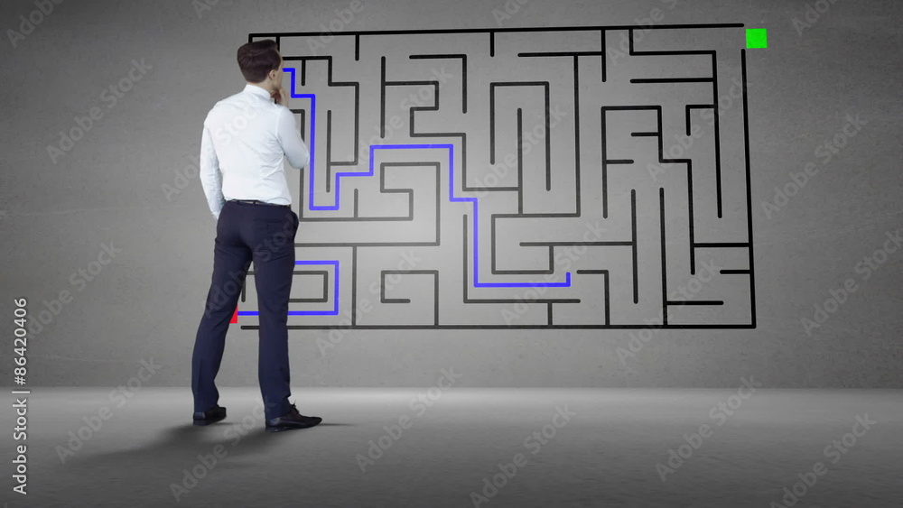Businessman looking at grey wall with maze Businessman looking at grey wall with maze