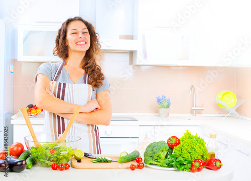 Happy young woman cooking in the kitchen at home