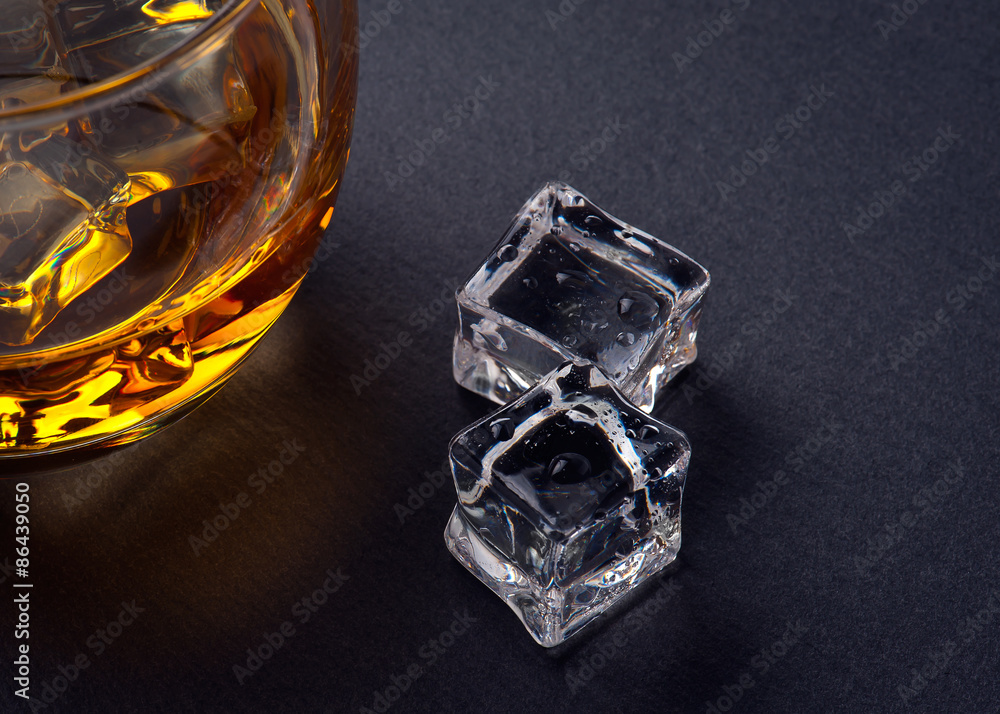 Glass of whiskey with ice on black stone table. Top view with copy space Glass of whiskey with ice on black stone table. Top view with copy space