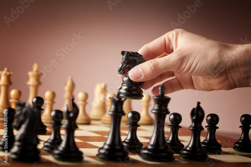 Male hand moving the black chess knight during the game of chess