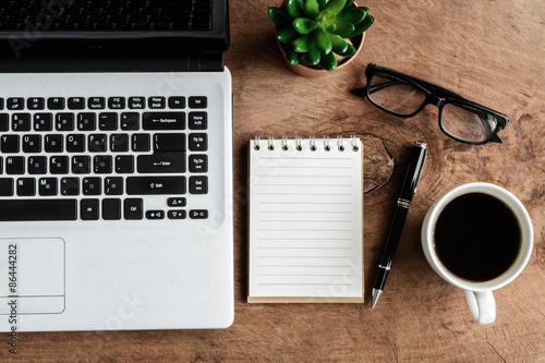 Laptop and cup of coffee on old wooden table