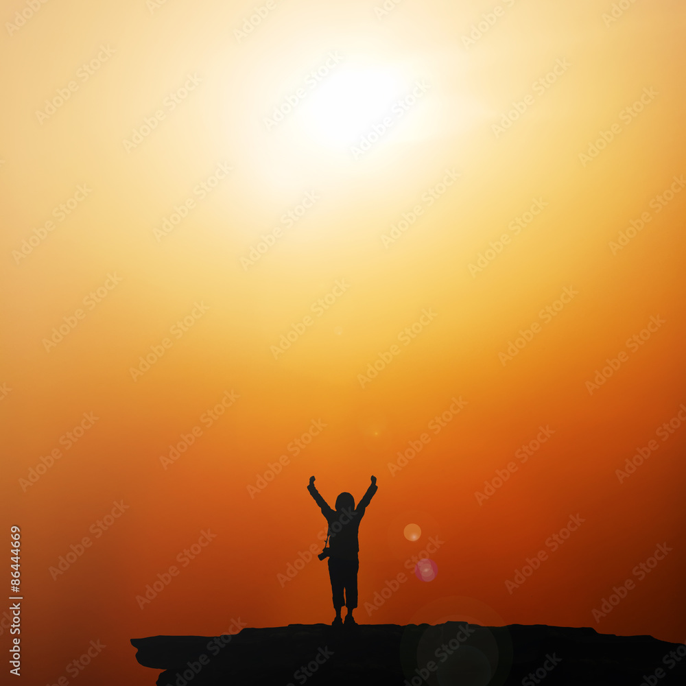 Silhouette of traveller with hands raised to the sun at  sunrise