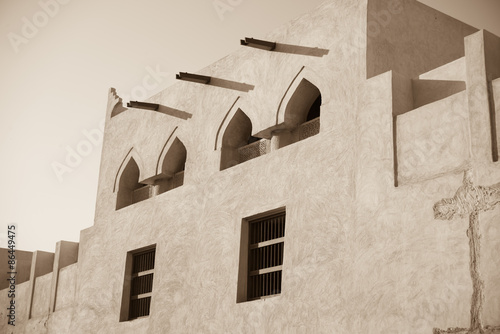 Exterior adobe wall of restored Isa bin Ali House, Muharraq, Bahrain showing arched windows, wooden window frames and water guttering.