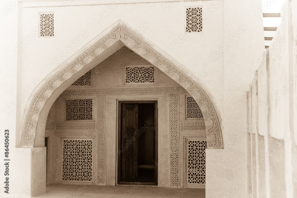 The entrance to a room in the restored Isa bin Ali house in Muharraq, Bahrain shows elaborate plasterwork on the wall and ogee archway including lattices to allow air circulation.