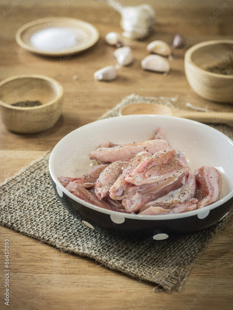 Raw chicken and ingredient in bowl on wooden table Raw chicken and ingredient in bowl on wooden table