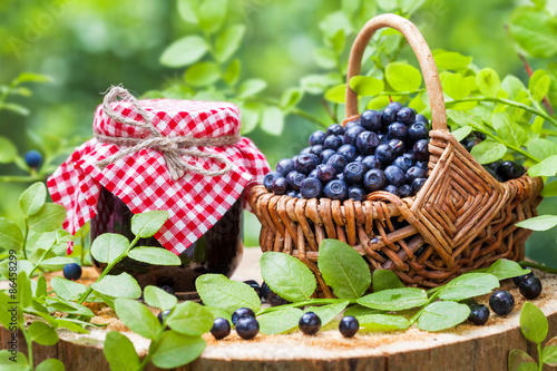 Jars of jam and basket with wild blueberries