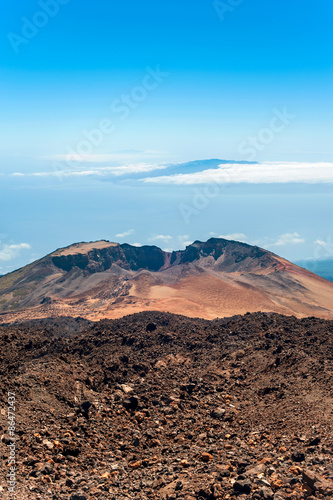 Crater of Pico Viejo volcano on a blue cloudscape background. Multicolored outdoors image.