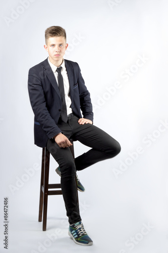 A young boy, brunette with short hair, a student in a black suit