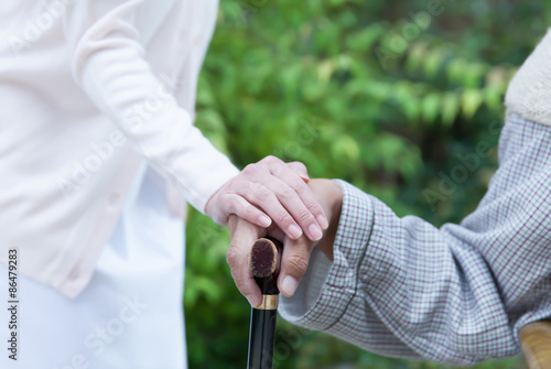 杖を握った男性患者の手に手を添える女性看護師 © tomoco_sozai