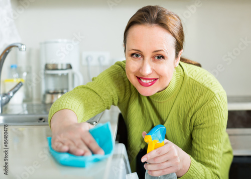 Housewife cleaning furniture in kitchen