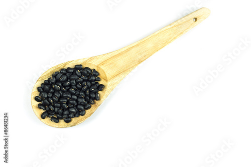 Black beans in wooden spoon isolated on white