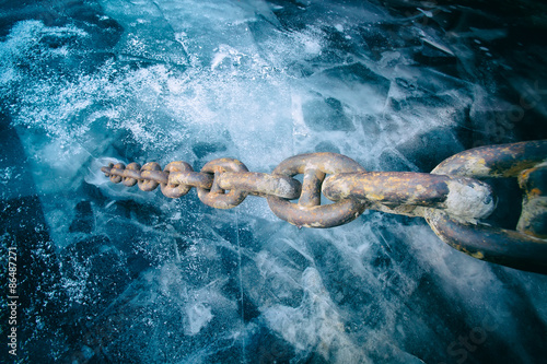 Tightly stretched chain frozen in the ice photo