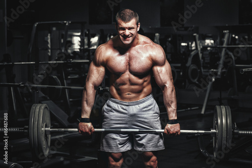 Athlete muscular bodybuilder in the gym training with barbell