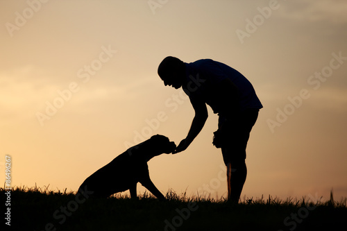 Fototapeta Naklejka Na Ścianę i Meble -  Hund und Herrchen als Silhouette bei Sonnenuntergang