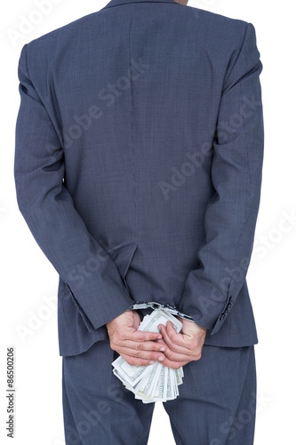 businessman in handcuffs holding bribe