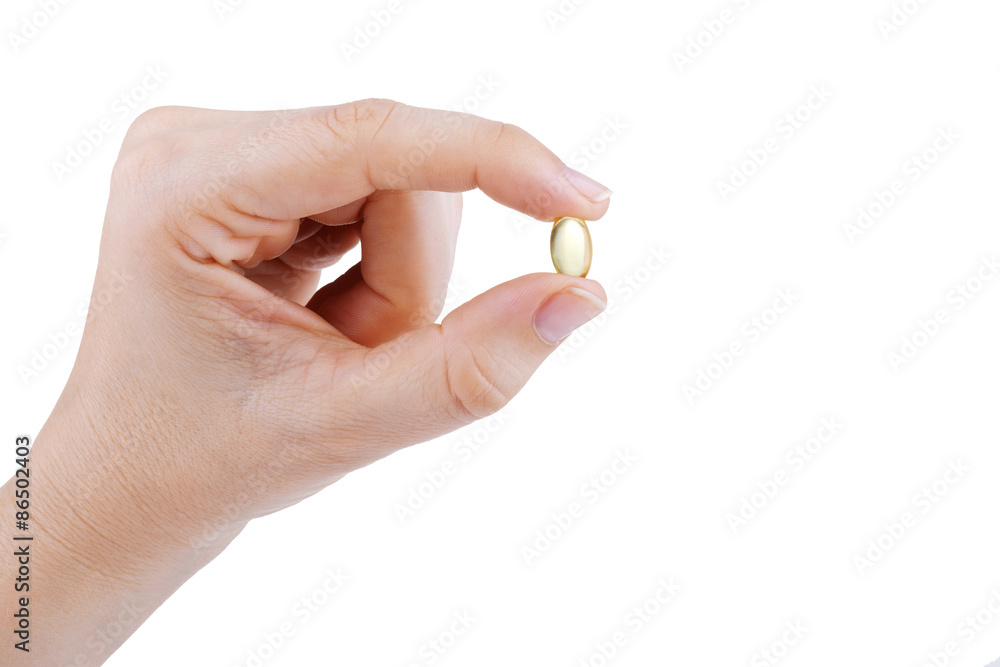 Woman's hand holding transparent yellow pill Woman's hand holding transparent yellow pill