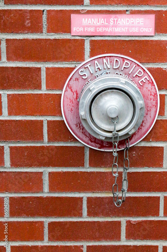 Manual standpipe on a red brick building for use by the fire department in case of fire photo