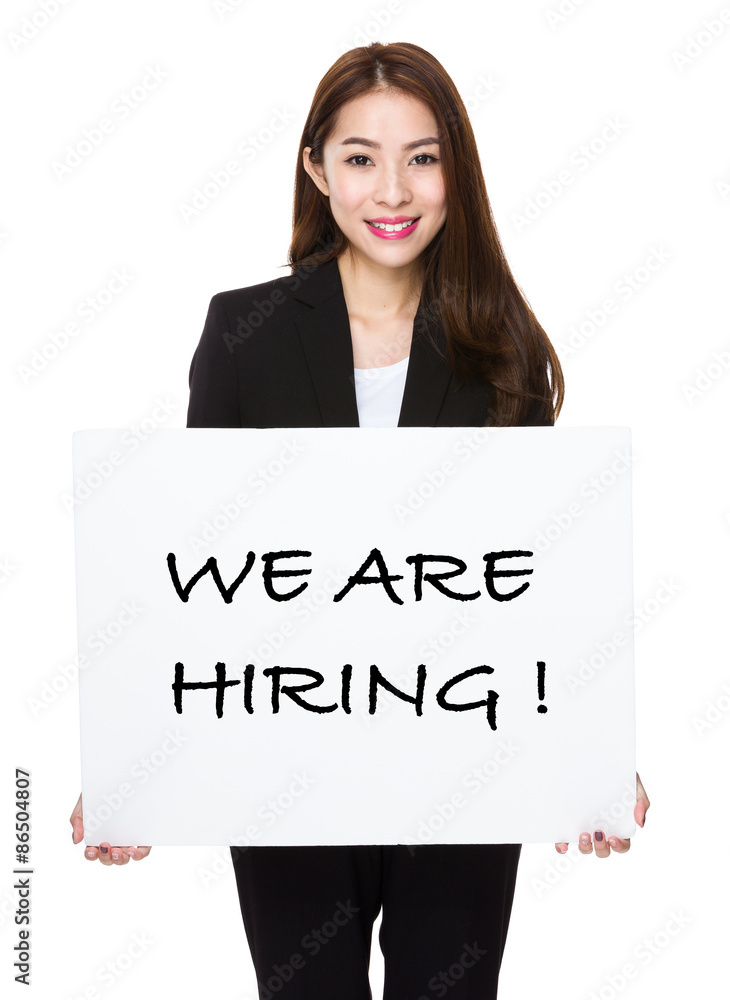 Businesswoman showing a board showing with we are hiring phrases Businesswoman showing a board showing with we are hiring phrases