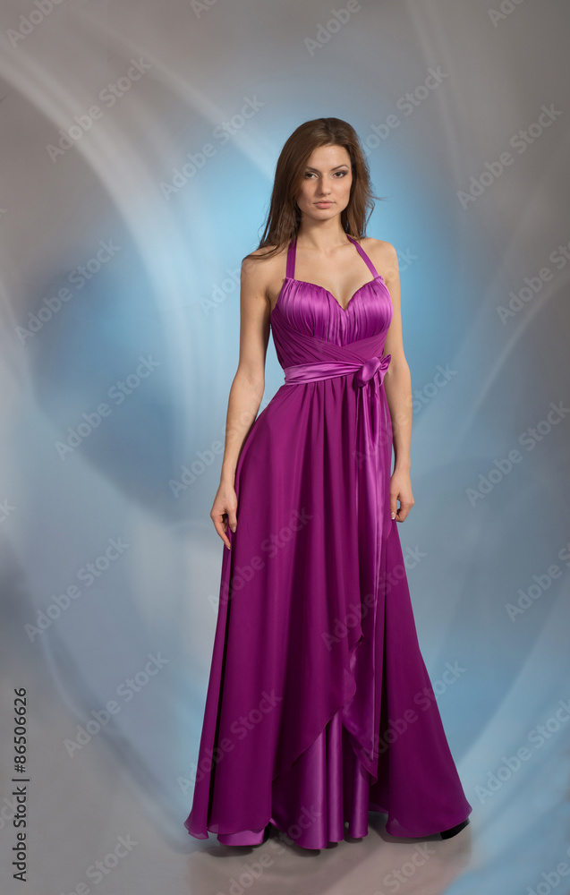 Full-length portrait of a girl posing in plum violet evening dress