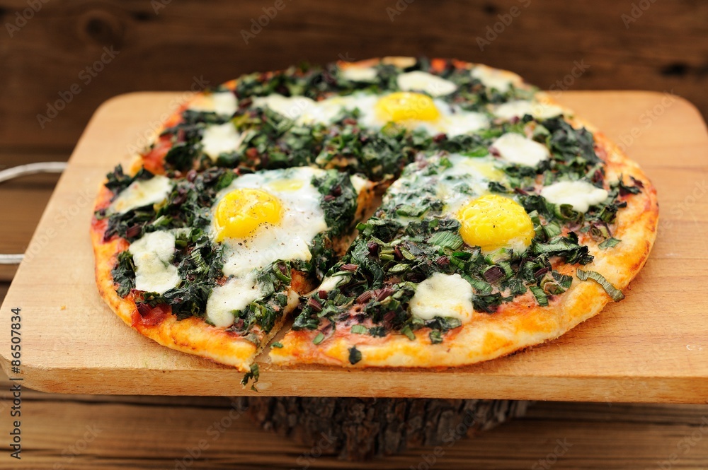 Round green pizza with eggs and mozarella on wooden board