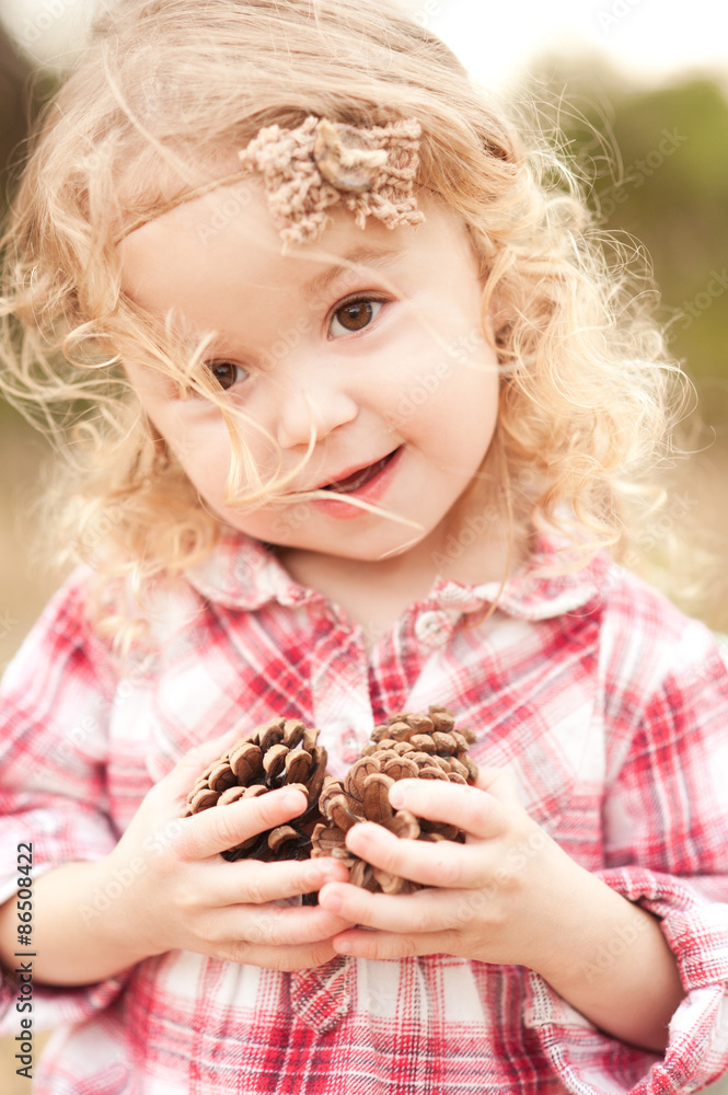 Cute baby girl 2-3 year old holding pine cones outdoors. Looking at camera. Childhood. Playful. Cute baby girl 2-3 year old holding pine cones outdoors. Looking at camera. Childhood. Playful.