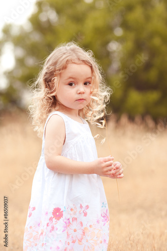 Little baby girl 2-3 year old walking in meadow. Nature. Looking at camera. Childhood.