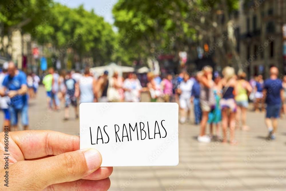 Fototapeta premium man shows a signboard with the text Las Ramblas, at Las Ramblas